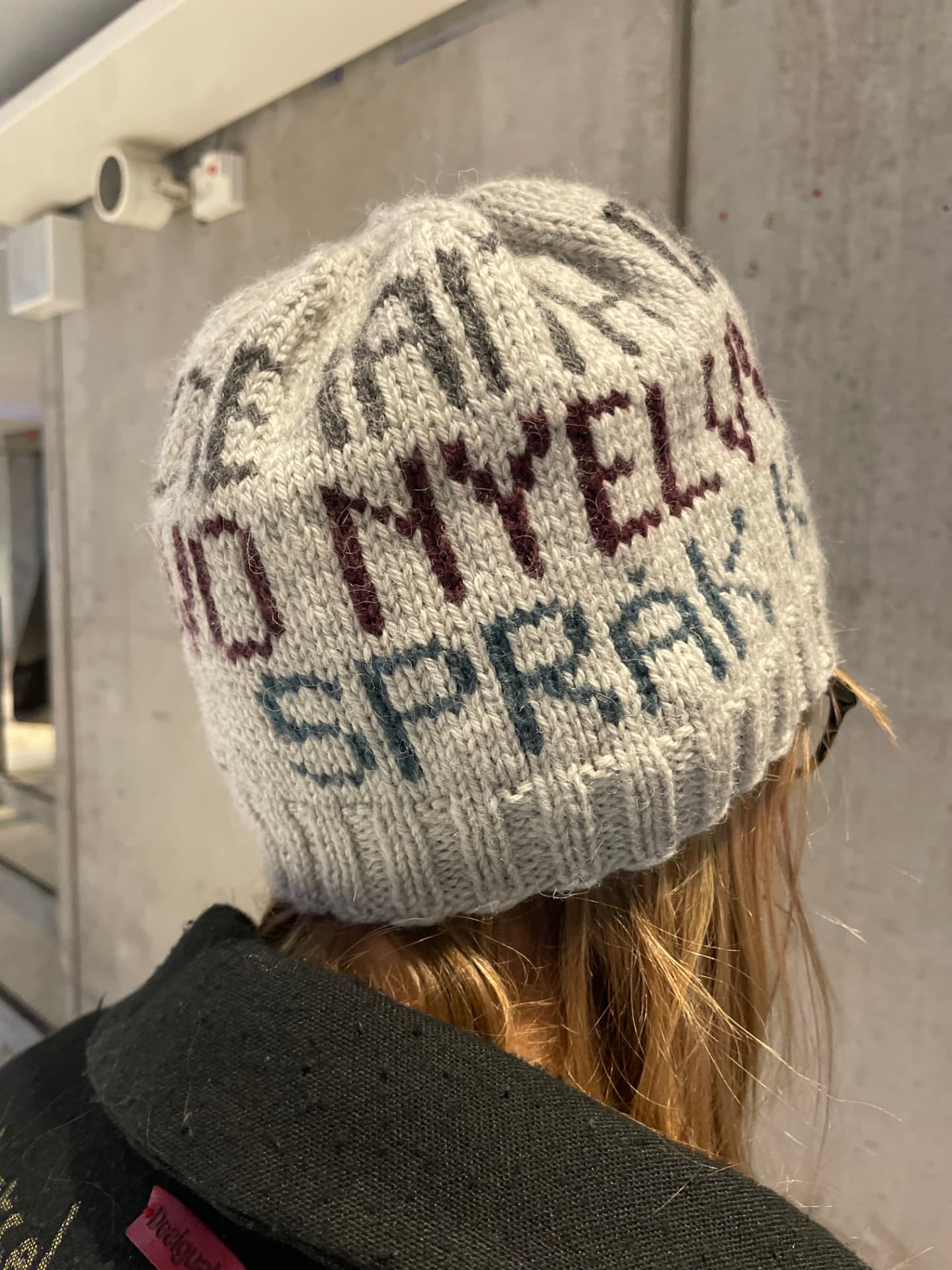 Stickad mössa med texten RUM FÖR SPRÅK