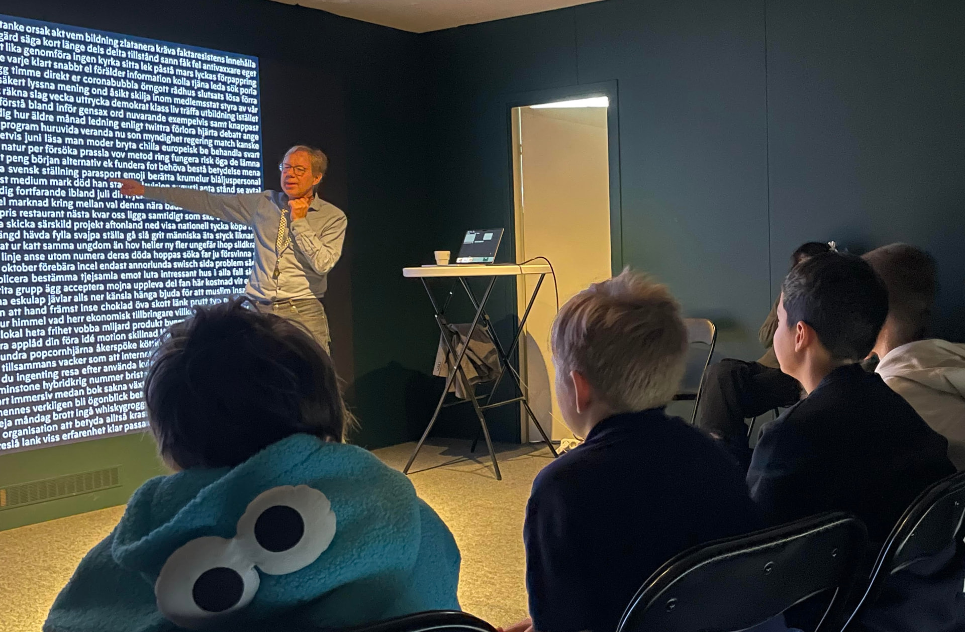 Pedagog leder skolklass i programmet Svenska ord framför en vägg av projicerade ord